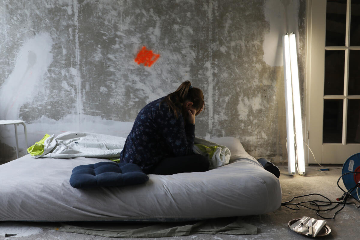 Vrouw op matras in vervuilde kamer